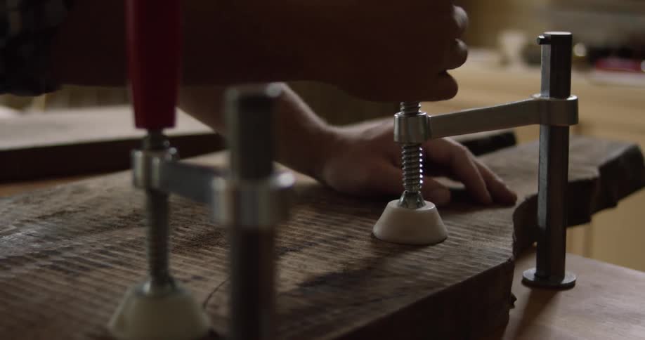A man adjusting a clamp on a workbench