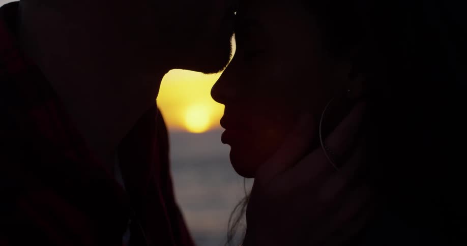 A man embraces a woman and kisses her forehead on the beach