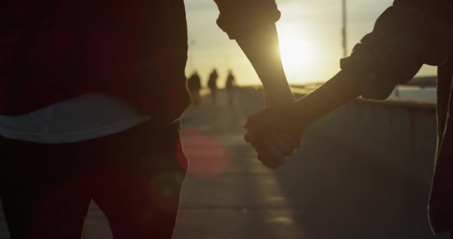 A man and woman hold hands as they walk