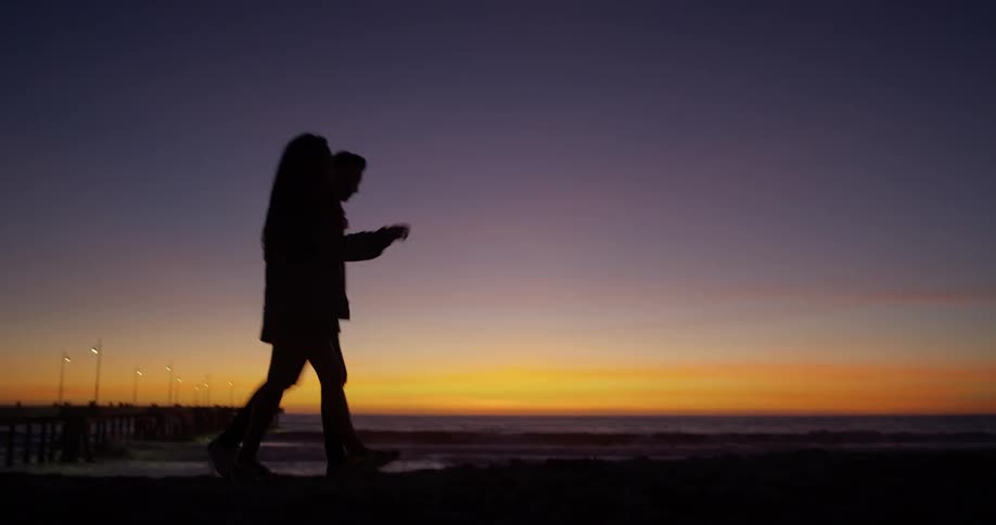A man and woman walk together by the beach