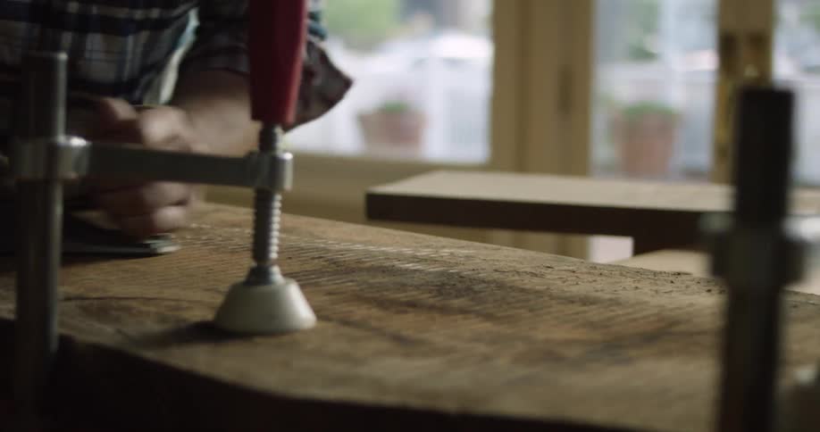 A man using a hand tool to sand a surface