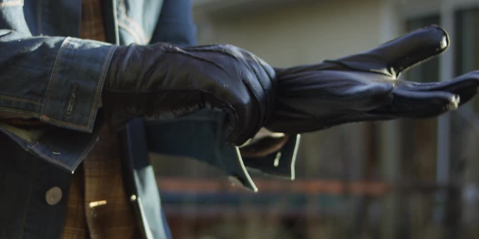 A man puts black leather gloves on