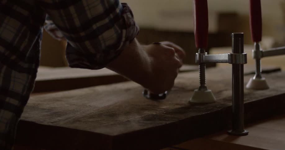 A man shaves and smooths a piece of wood