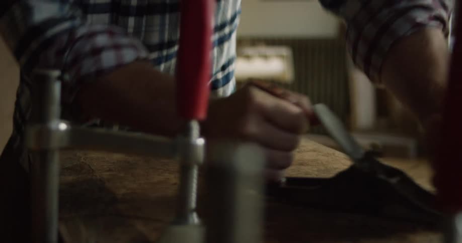 A man shaves and smooths a piece of wood