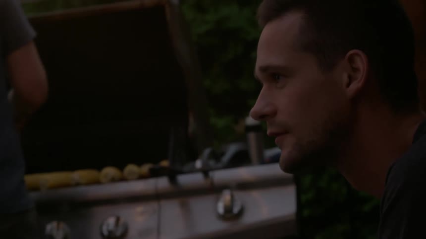 Men talking and preparing food during a cookout on a deck