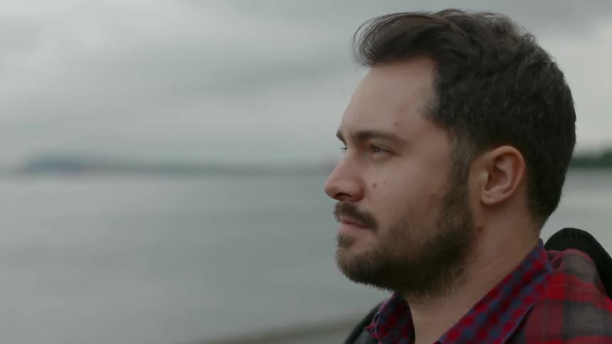A man looking out over a body of water that has a ship docked