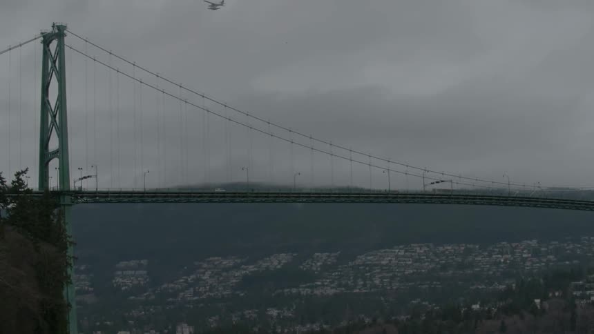 Vehicles cross a city bridge as an airplane flies overhead