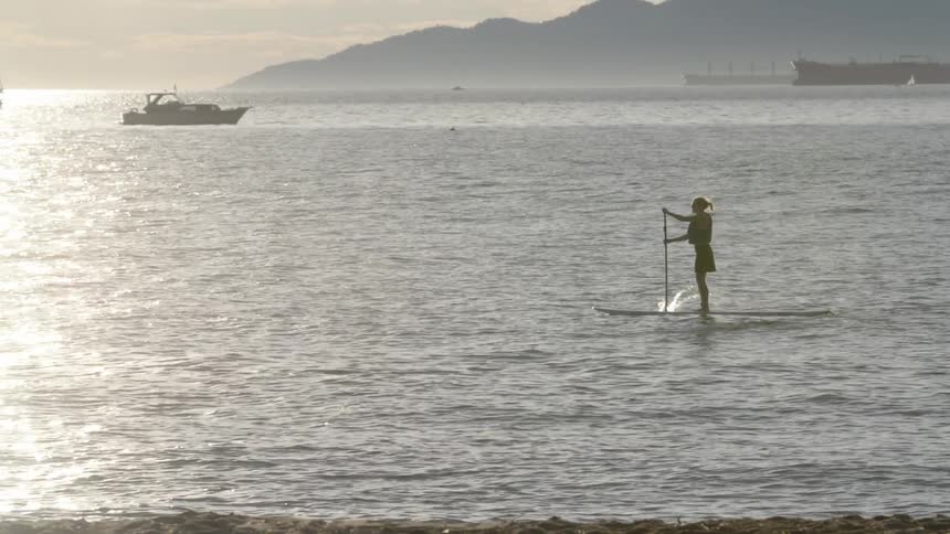 A woman paddles and floats on the ocean