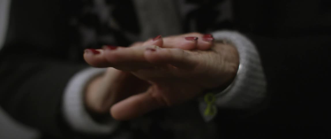 An elderly woman wearing red nail polish rubbing the bottom and top of her hand