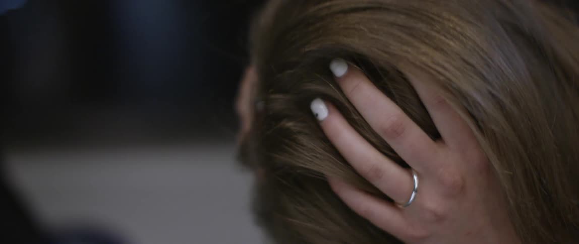 A woman holds her head as she bends forward