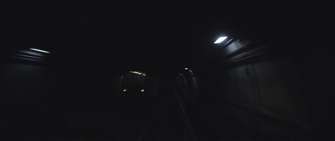 The view in a dark subway train tunnel as you meet another train
