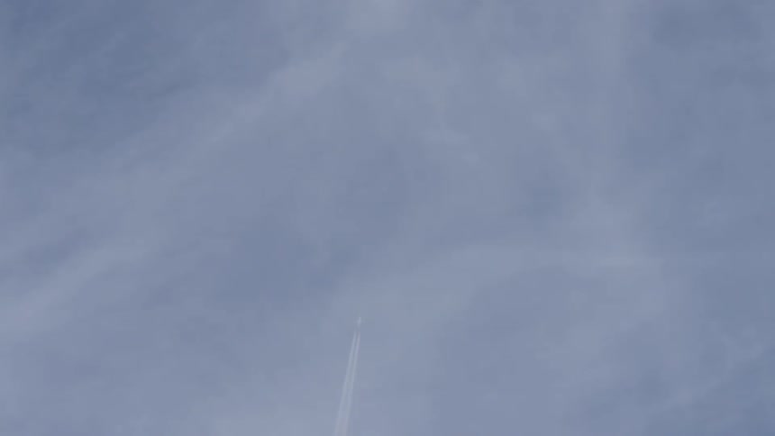 A jet trail extends into the blue sky