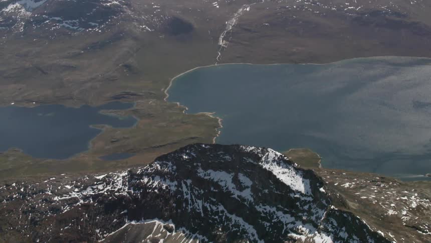 A view of snow capped mountains with a body of water in the valley
