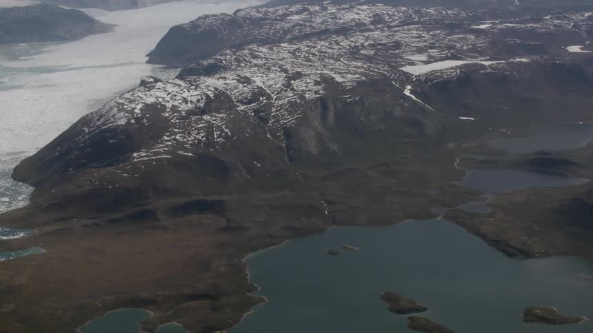 A snow covered mountain surrounded by water is shown from above