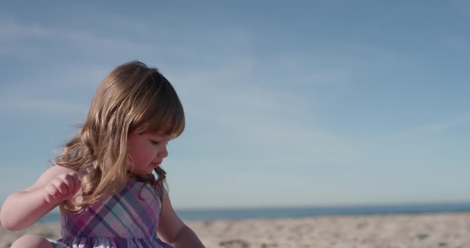 A young girl plays in the sand on the beach