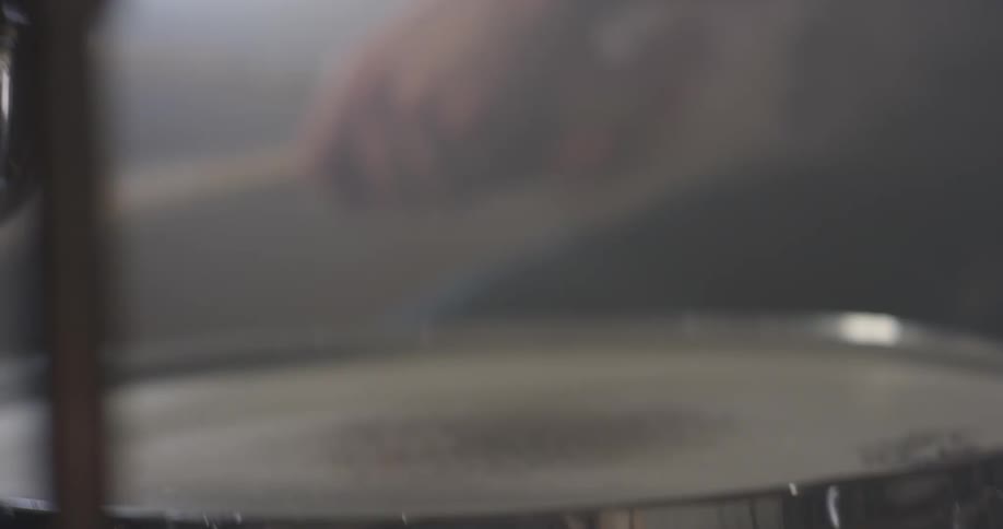 Person hits a snare drum with a drumstick