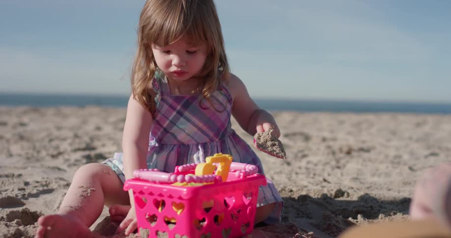 A young girl plays with plastic toys on the beach