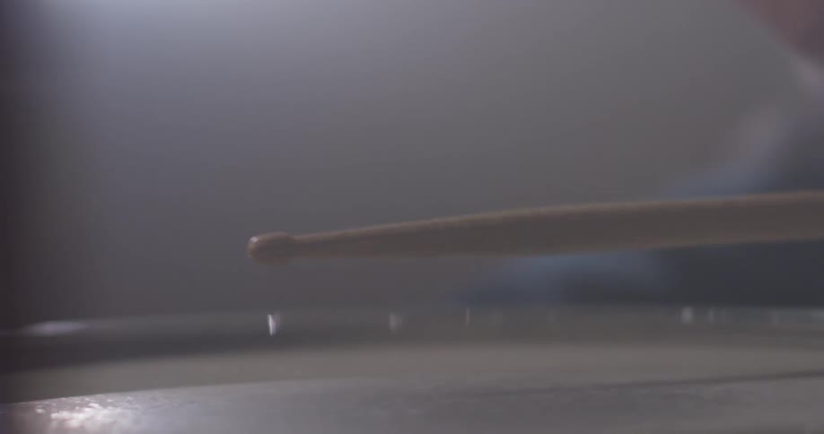 A musician plays the drums with drum sticks