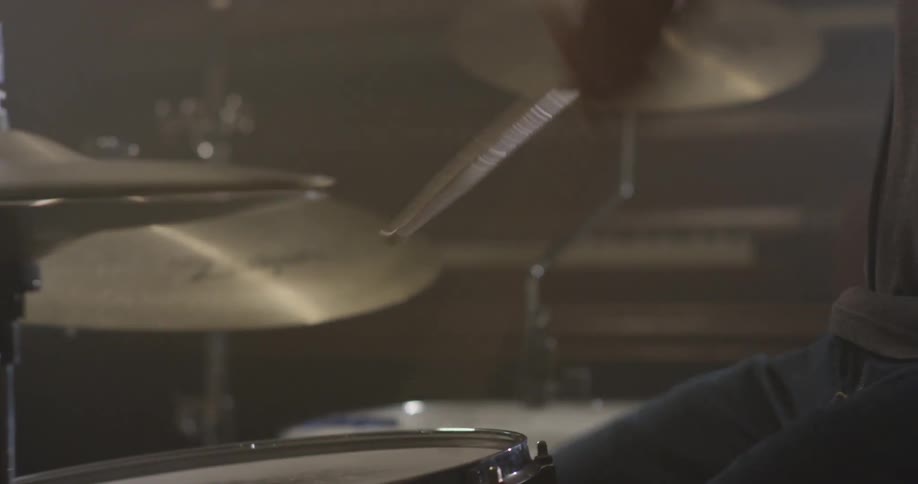 A drummer is playing drums indoors in daylight
