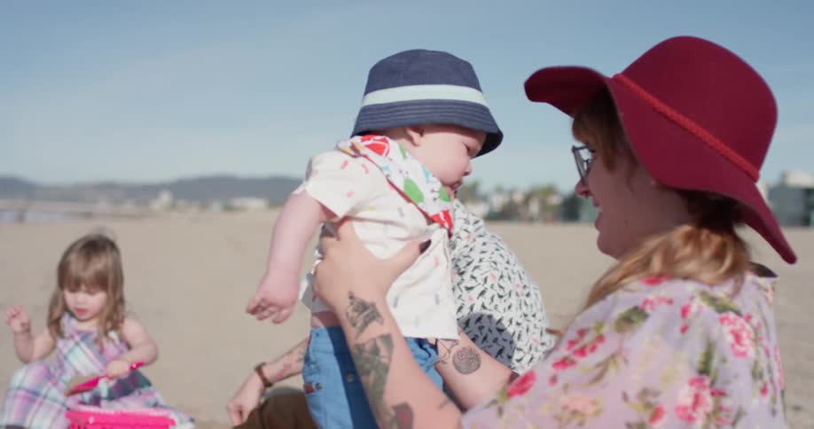 A mother holds a baby on a sunny beach
