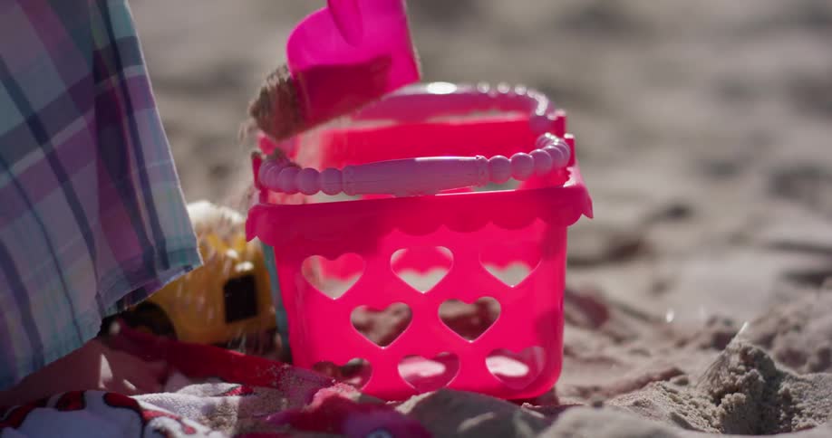 A young girl plays with plastic toys on the beach