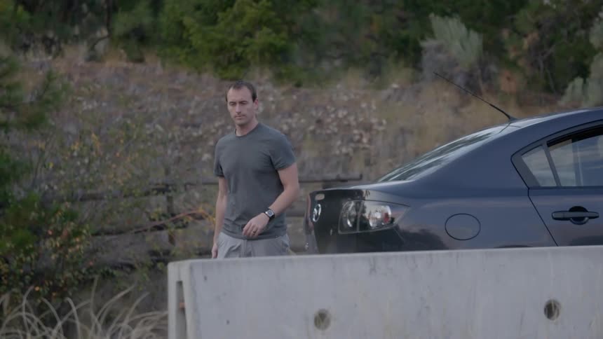 A man walks around the rear of his car