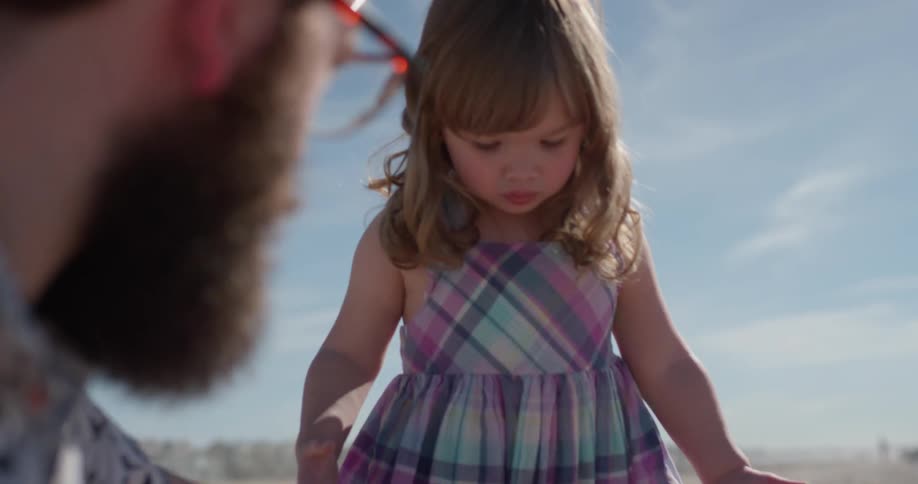 Child talks to a man while man brushes child's dress off