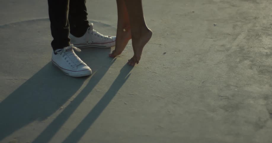 A woman stands on her toes as she approaches a man