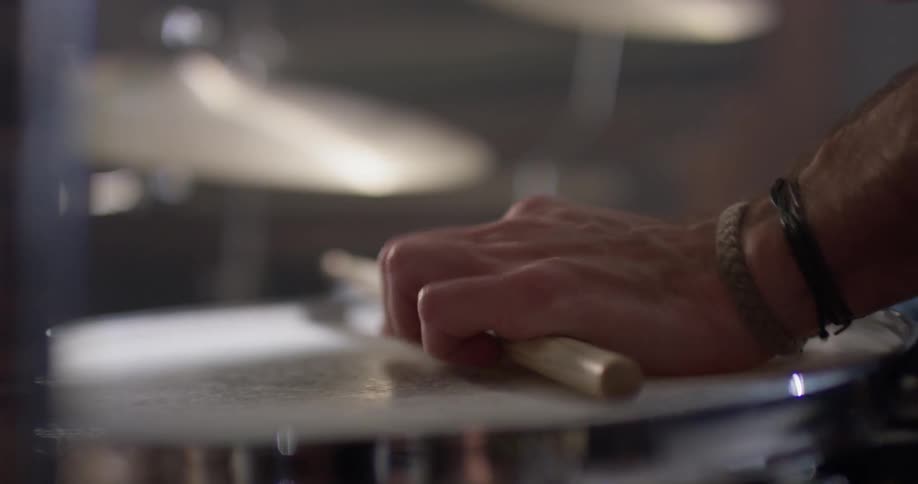 A man taps the stick on the snare drum