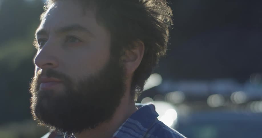 A man in a beard looks around outside