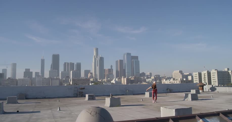 A woman dances on a building rooftop