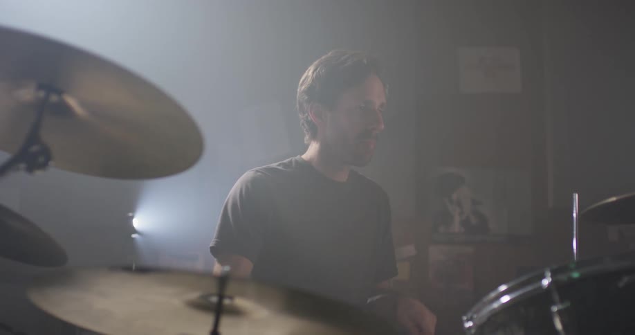 A man plays drums in a garage