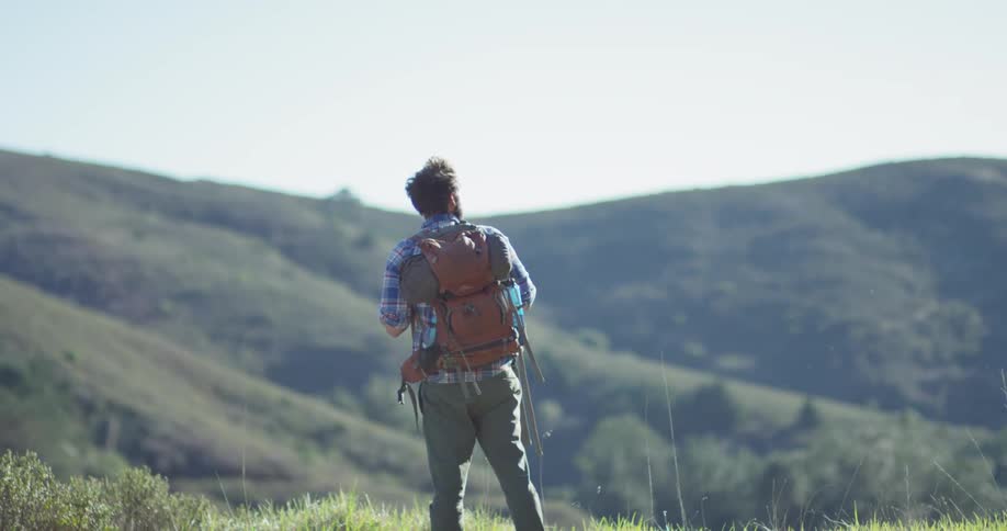 A hiker stops to look at the mountains
