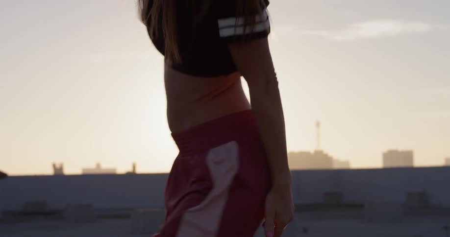A woman dances on a building rooftop