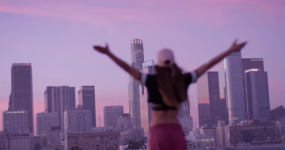 Woman raises her arms outside in the city