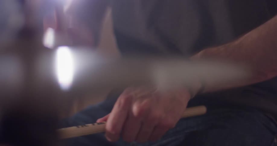 A man plays drums with drumsticks