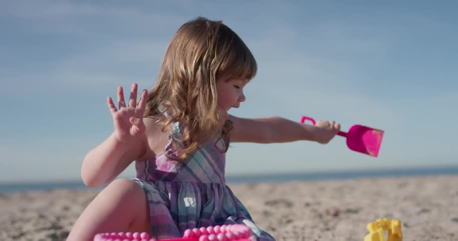 A young girl plays with plastic toys on the beach
