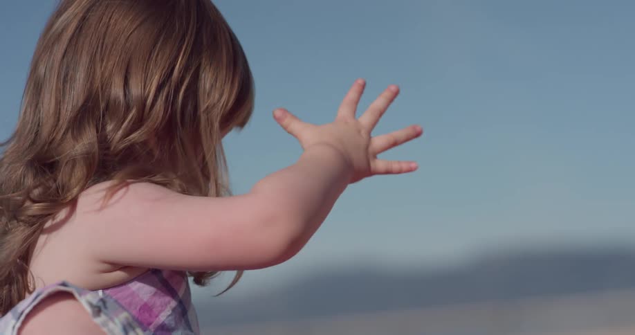 A young girl plays with sand on the beach