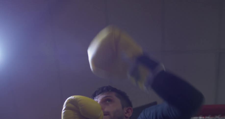 A man wearing boxing gloves hits the speed bag