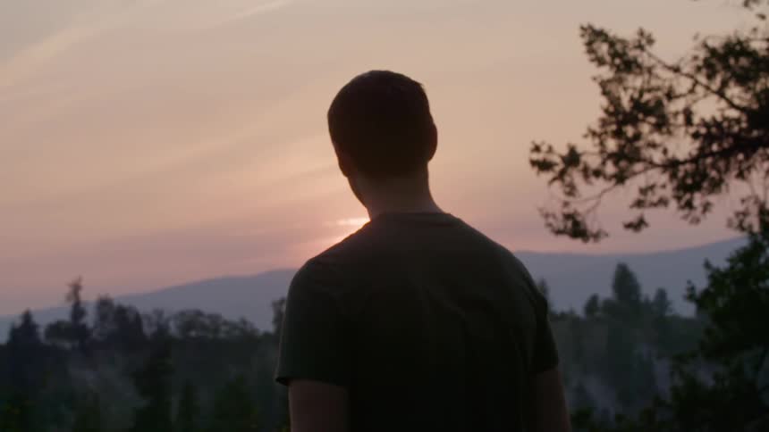 A man stands and watches the sunset