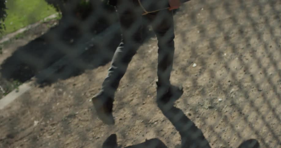 The person is walking behind the fence