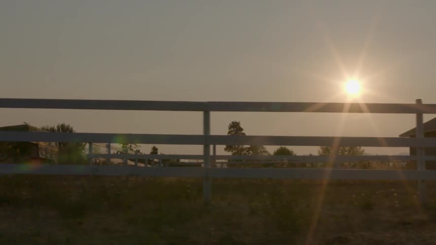 A rural home with horse fencing seen from a moving vehicle