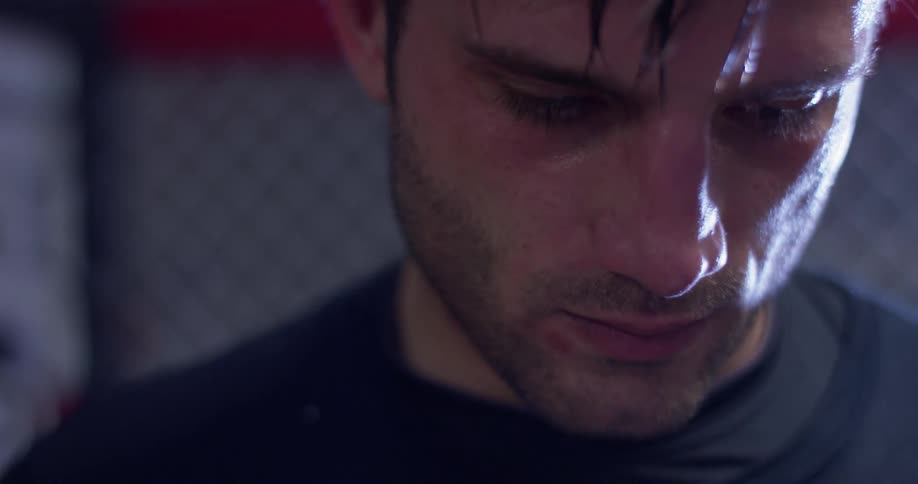 A man stands and looks down inside a martial arts ring