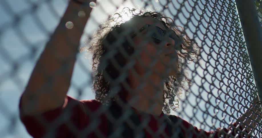 A man walks up to a tall chain link fence