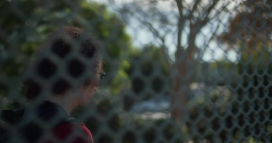 Young person walks next to a chain link fence