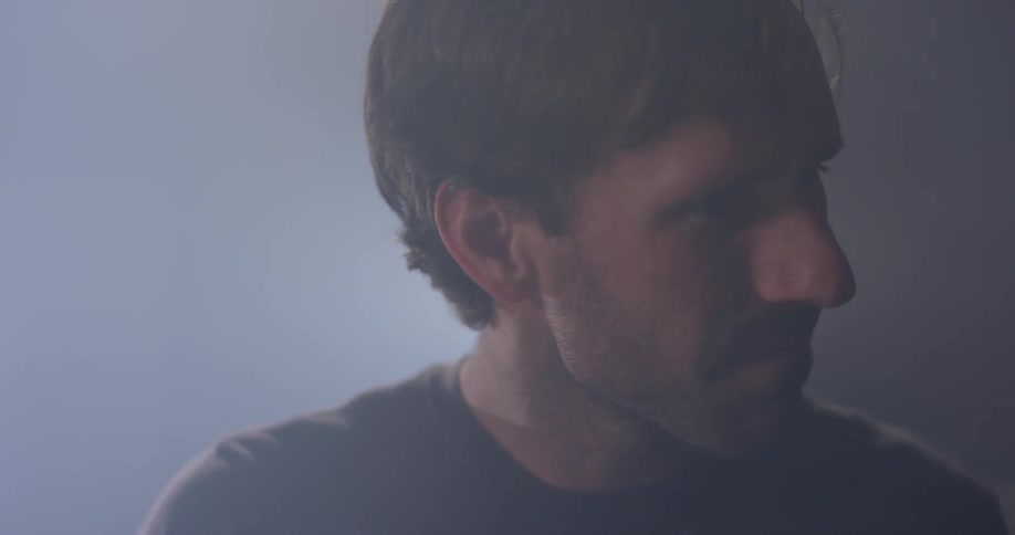 A man nods his head while playing drums