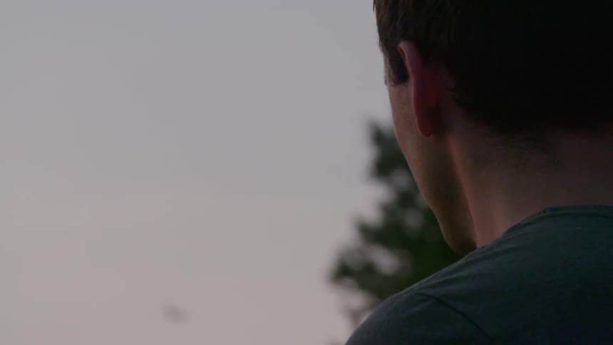 A man watches a jet fly overhead