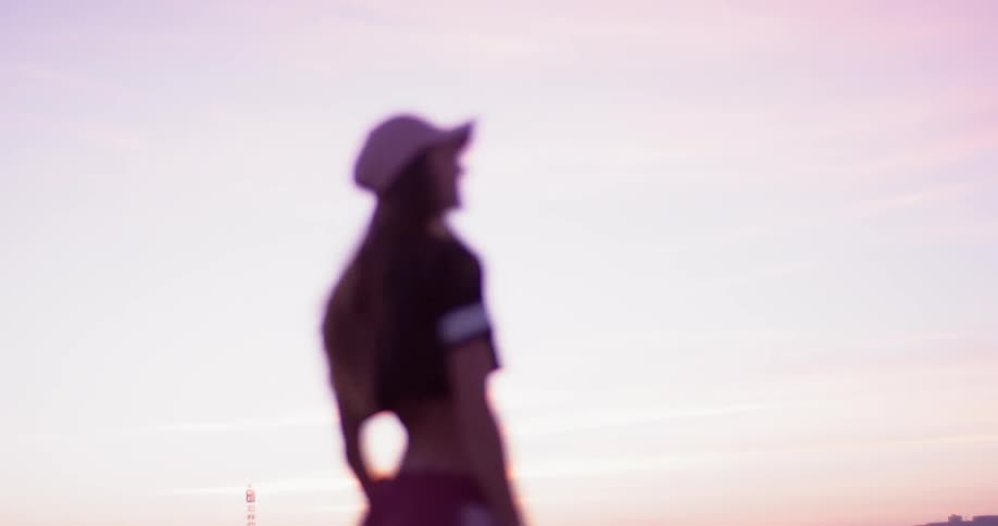 A woman in a pink hat stands atop a rooftop