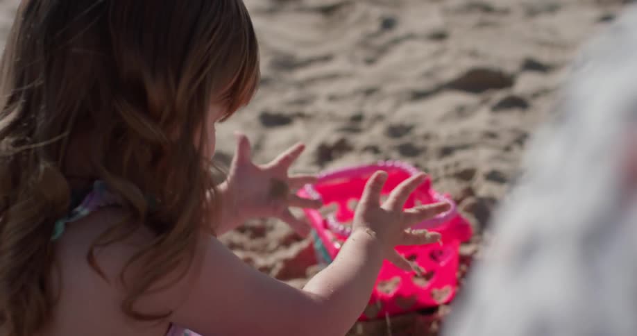 A young girl plays in the sand on the beach