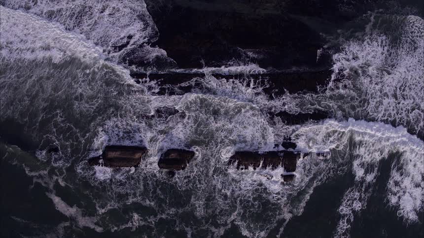 Ocean waves crash up onto large rocks